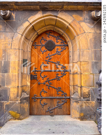 An antique Gothic-style wooden door featuring wrought-iron ornamentation 142692105