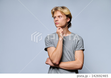 Portrait of thoughtful teenage boy looking away with hand on chin 142692465