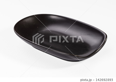 Black oval ceramic dish with smooth glossy finish on white background, minimalist design, shallow depth, soft shadow, studio lighting Black oval ceramic dish with smooth glossy finish on white background, minimalist design, shallow depth, soft shadow, studio lighting 142692893