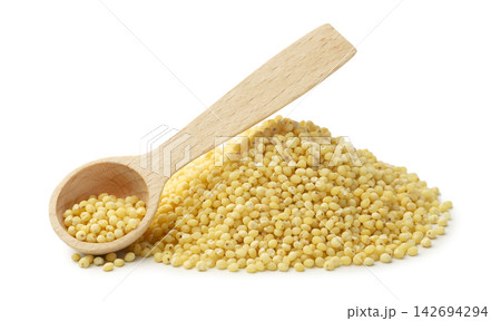 A pile of raw millet and a wooden spoon in close-up on a white background. Isolated A pile of raw millet and a wooden spoon in close-up on a white background. Isolated 142694294