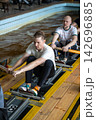 Tired male rowers pushing through powerful catch position during intensive indoor training 142696885