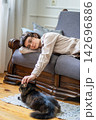 Tired young woman lying on sofa and gently petting beloved cat for emotional comfort at home 142696886