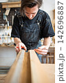 Carpenter making measurements for patch replacement on vintage wooden window frame in repair shop. 142696887