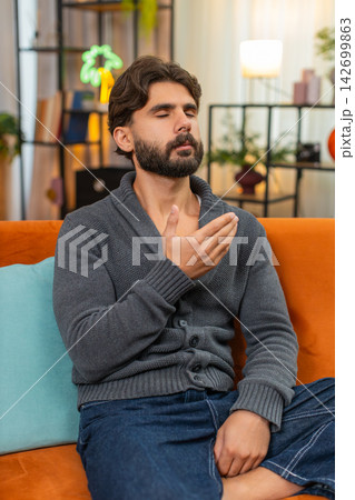 Indian man with closed eyes repeats quiet words palms together silent prayer calm breath mood softly 142699863