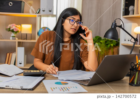 Indian woman on home table calls about billing error and discusses wrong charge on receipt by phone Indian woman on home table calls about billing error and discusses wrong charge on receipt by phone 142700572