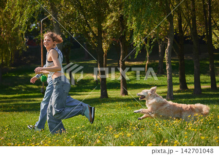 Young couple runs across park as golden retriever playfully follows Young couple runs across park as golden retriever playfully follows 142701048