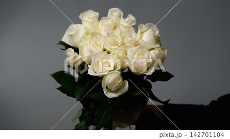 The florist holds a bouquet of beautiful white roses. The bouquet was made to order. 142701104