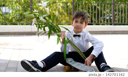 Schoolboy with Flowers and Skateboard on September 1, First Day of School, Back to School, Knowledge Day, Modern Student and School Life Schoolboy with Flowers and Skateboard on September 1, First Day of School, Back to School, Knowledge Day, Modern Student and School Life 142701162