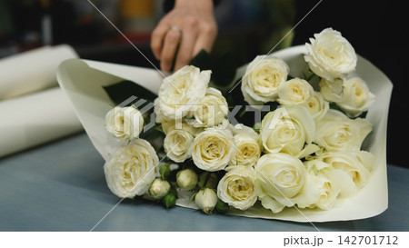 Beautiful white roses in a flower shop. Florist assembles a bouquet to order 142701712