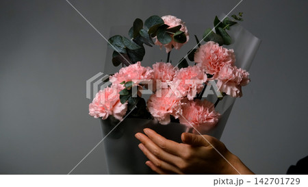 Bouquet of pink carnations on a gray background. Florist assembly a bouquet to order 142701729