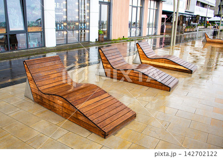 Empty wet deck chairs by beach in rain. Summer vacation ruined by bad weather. Cold rainy season disappoints tourists. No people sunbathing due to weather Empty wet deck chairs by beach in rain. Summer vacation ruined by bad weather. Cold rainy season disappoints tourists. No people sunbathing due to weather 142702122
