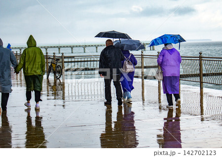 Tourists exploring new city despite heavy rain using umbrellas and raincoats for water protection. Bad weather does not stop travel concept. Rainy day travel hacks 142702123