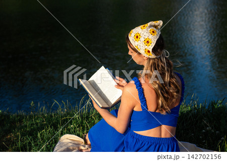 Young woman reading book in summer park. Digital detox in action. Intentional escape from screens. Brain reset through nature and words. Mindfulness among green trees. Book lovers day Young woman reading book in summer park. Digital detox in action. Intentional escape from screens. Brain reset through nature and words. Mindfulness among green trees. Book lovers day 142702156