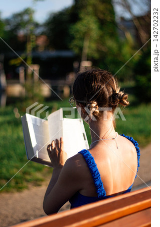 Woman reading in sunlit park. No smartphone. Cognitive refresh through pages. Self education in priority. Celebrating August 9 book lovers day 142702232
