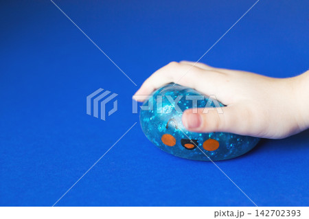 Child's hand squeezing blue stress ball for anxiety relief Child's hand squeezing blue stress ball for anxiety relief 142702393