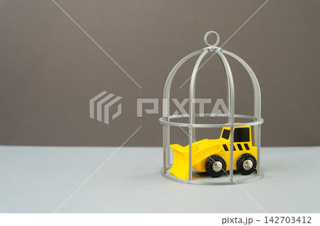 A bulldozer locked under a cage. Concept of freezing destructive works and construction. Symbol of halted development, regulation and environmental protection policy. A bulldozer locked under a cage. Concept of freezing destructive works and construction. Symbol of halted development, regulation and environmental protection policy. 142703412