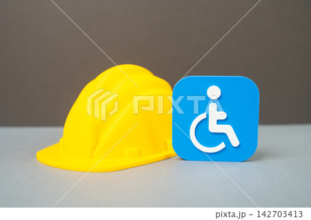 A disability symbol and a construction worker's hard hat. Concept of career and employment for people with disabilities. Building an accessible barrier-free environment. A disability symbol and a construction worker's hard hat. Concept of career and employment for people with disabilities. Building an accessible barrier-free environment. 142703413