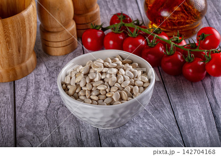 White beans in textured ceramic bowl with cherry tomatoes on vine, wooden salt mill and pepper grinder, saffron in glass jar on grey wood table White beans in textured ceramic bowl with cherry tomatoes on vine, wooden salt mill and pepper grinder, saffron in glass jar on grey wood table 142704168