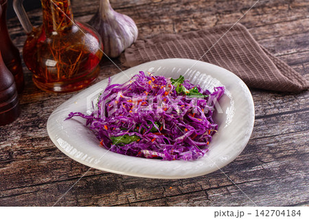 Shredded purple cabbage salad with fresh herbs and red pepper flakes in white ceramic bowl on rustic wooden table Shredded purple cabbage salad with fresh herbs and red pepper flakes in white ceramic bowl on rustic wooden table 142704184