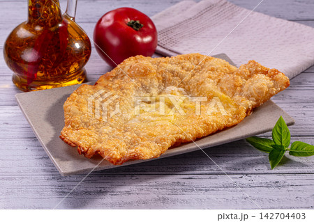 Golden fried cheburek on square plate with fresh tomato, basil leaves and oil bottle on rustic white wood background Golden fried cheburek on square plate with fresh tomato, basil leaves and oil bottle on rustic white wood background 142704403