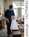 Thoughtful master carpenter checking surface of wooden frame after processing detail with hand plane 142704442