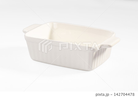 Empty white ceramic baking dish with ribbed sides and handles on clean white background 142704478