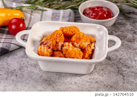 Crispy fried chicken nuggets in white ceramic dish with ketchup, cherry tomato, yellow pepper, and rosemary on gray stone surface Crispy fried chicken nuggets in white ceramic dish with ketchup, cherry tomato, yellow pepper, and rosemary on gray stone surface 142704510