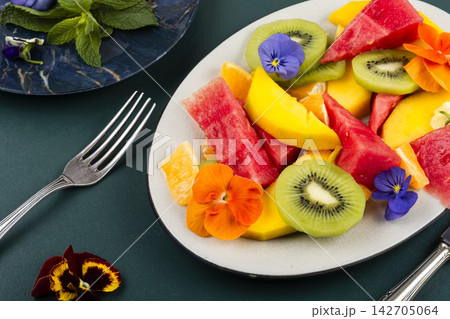 Exotic fruit salad decorated with edible flowers. Exotic fruit salad decorated with edible flowers. 142705064