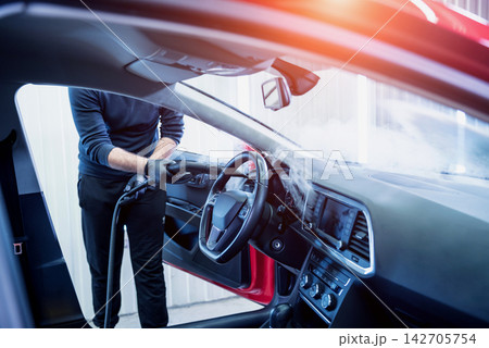 Car service worker cleans interiror with steam cleaner Car service worker cleans interiror with steam cleaner 142705754