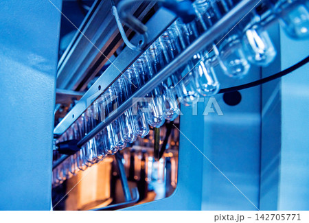 Automatic filling machine pours water into plastic PET bottles at modern beverage plant. 142705771