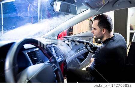 Car service worker cleans interiror with steam cleaner Car service worker cleans interiror with steam cleaner 142705858