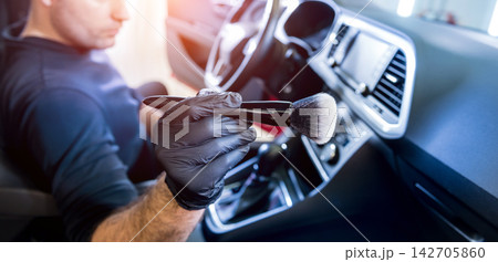 A car service worker cleans the car console with a special brush 142705860