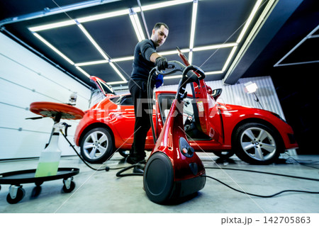 Car service worker cleaning car seat with a steam cleaner Car service worker cleaning car seat with a steam cleaner 142705863