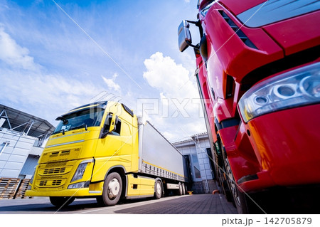 Large trucks near warehouse against blue sky background Large trucks near warehouse against blue sky background 142705879