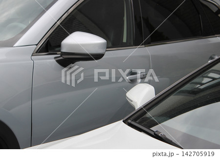Comparison of the height of a large SUV and a regular sedan parked next to it Comparison of the height of a large SUV and a regular sedan parked next to it 142705919