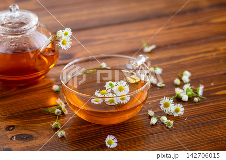 Relaxing herbal infusion with delicate white flowers on warm wooden table Relaxing herbal infusion with delicate white flowers on warm wooden table 142706015