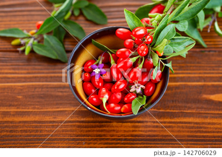 Fresh goji berries in ceramic bowl on wooden background 142706029