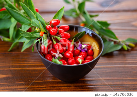 Ripe red goji berries with leaves on rustic wooden background 142706030