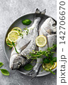 Fish raw dorado sea bream with lemon slices and herbs 142706670
