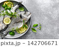 Fish raw dorado sea bream with lemon slices and herbs 142706671