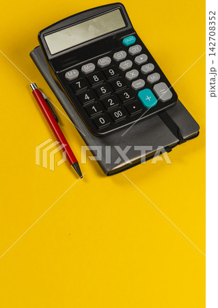 Calculator and notebook on a yellow desk for financial planning tasks 142708352