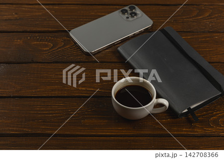 Coffee cup and smartphone on wooden desk during work break 142708366