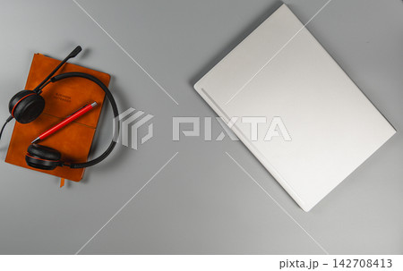 Headset and notebook placed on a work desk at home or office 142708413