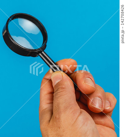 Holding a magnifying glass to search for small details Holding a magnifying glass to search for small details 142708426