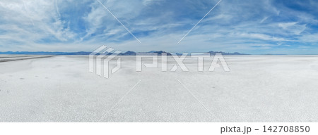 A wide drone view shows the vast white salt crust and mountains. A wide drone view shows the vast white salt crust and mountains. 142708850
