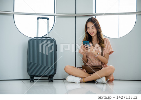 Traveler checking her flight and making plans for her trip using her smartphone at the airport 142711512