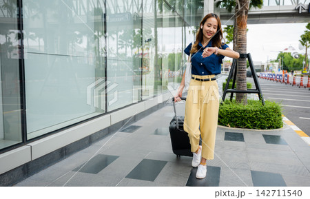 Woman waiting for her flight at the airport terminal with her luggage Woman waiting for her flight at the airport terminal with her luggage 142711540