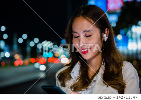 Young woman using modern smartphone in night city Young woman using modern smartphone in night city 142711547