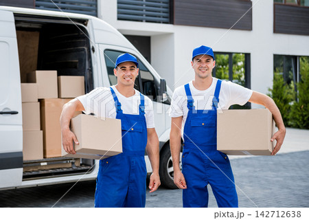 Two removal company workers unloading boxes from minibus into new home 142712638