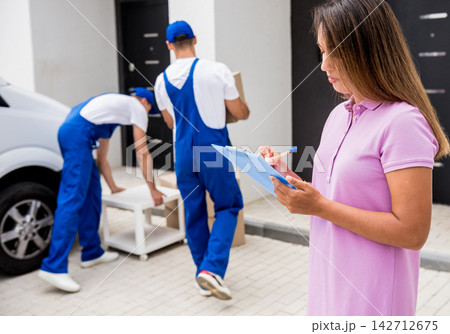 Two removal company workers unloading boxes from minibus into customer's home Two removal company workers unloading boxes from minibus into customer's home 142712675